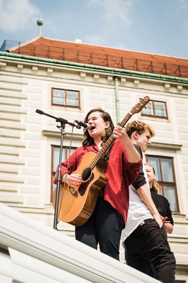 Isabel Frey plays guitar and sings at a protest