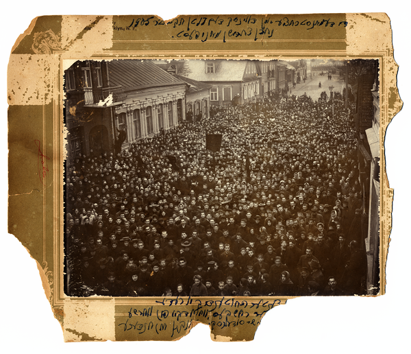 A scan of a sepia-toned photo of a huge crowd, some with banners