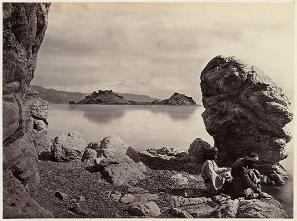 Sepia image of a rocky port on the red sea, with two men sitting in the foreground.